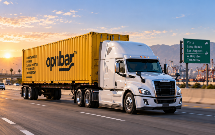 White semi truck hauling a yellow OPNBar intermodal container on a highway